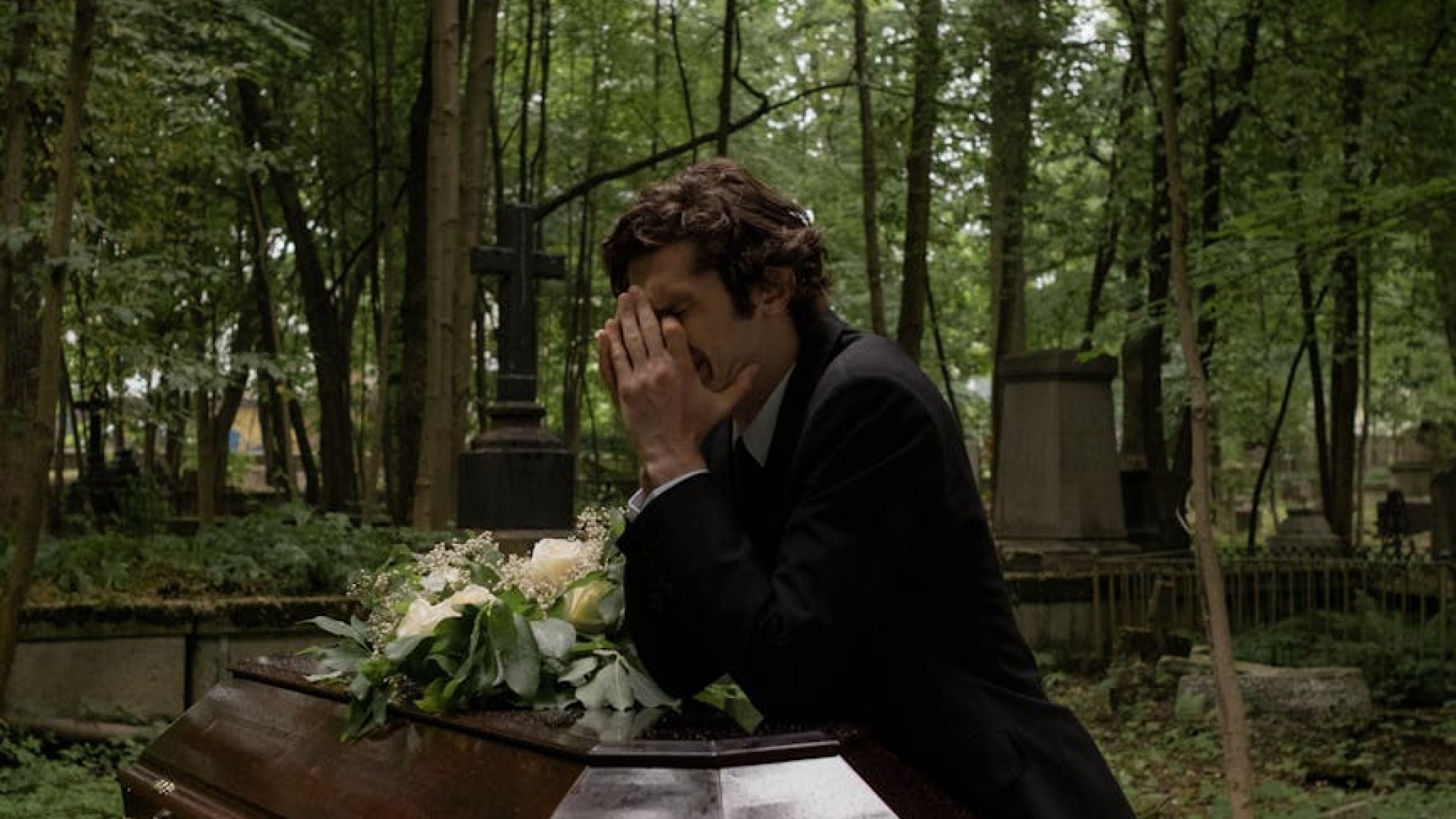 grieving man crying beside the coffin