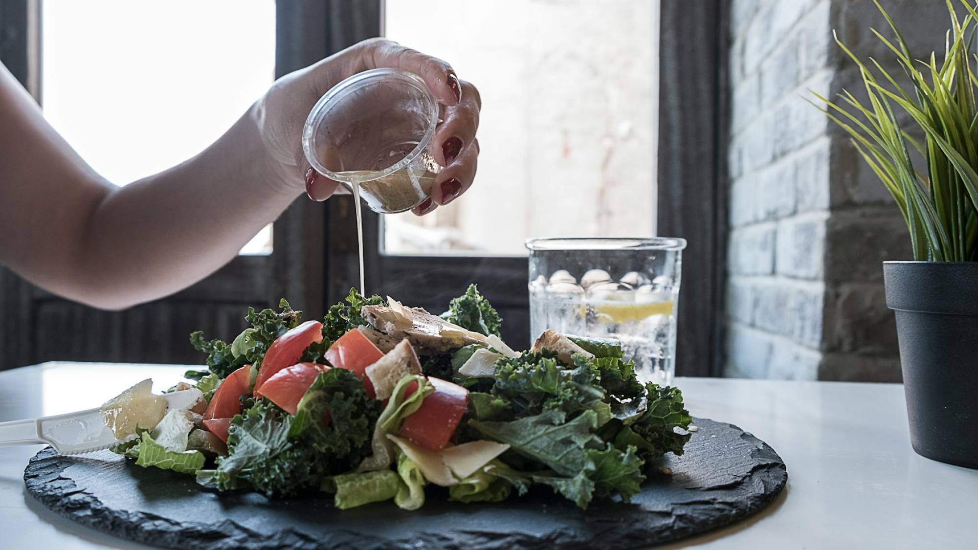 person pouring dip on vegetable salad