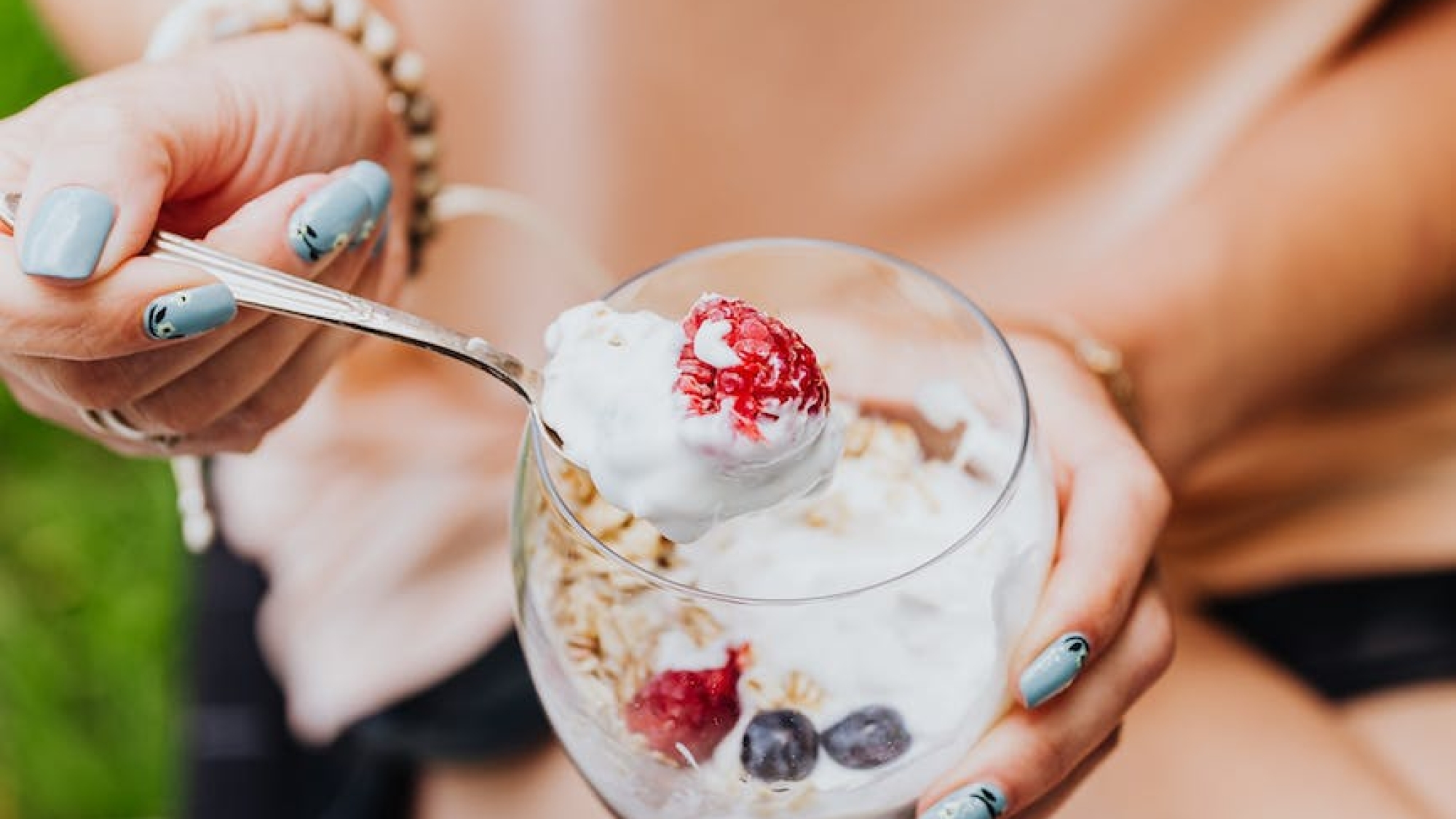 close up of woman eating yogurt with granola and fruit