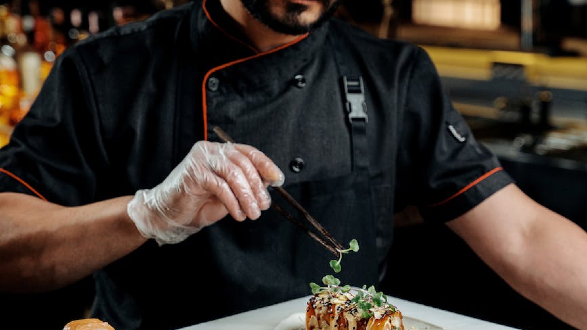 a chef garnishing sushi on a ceramic plate